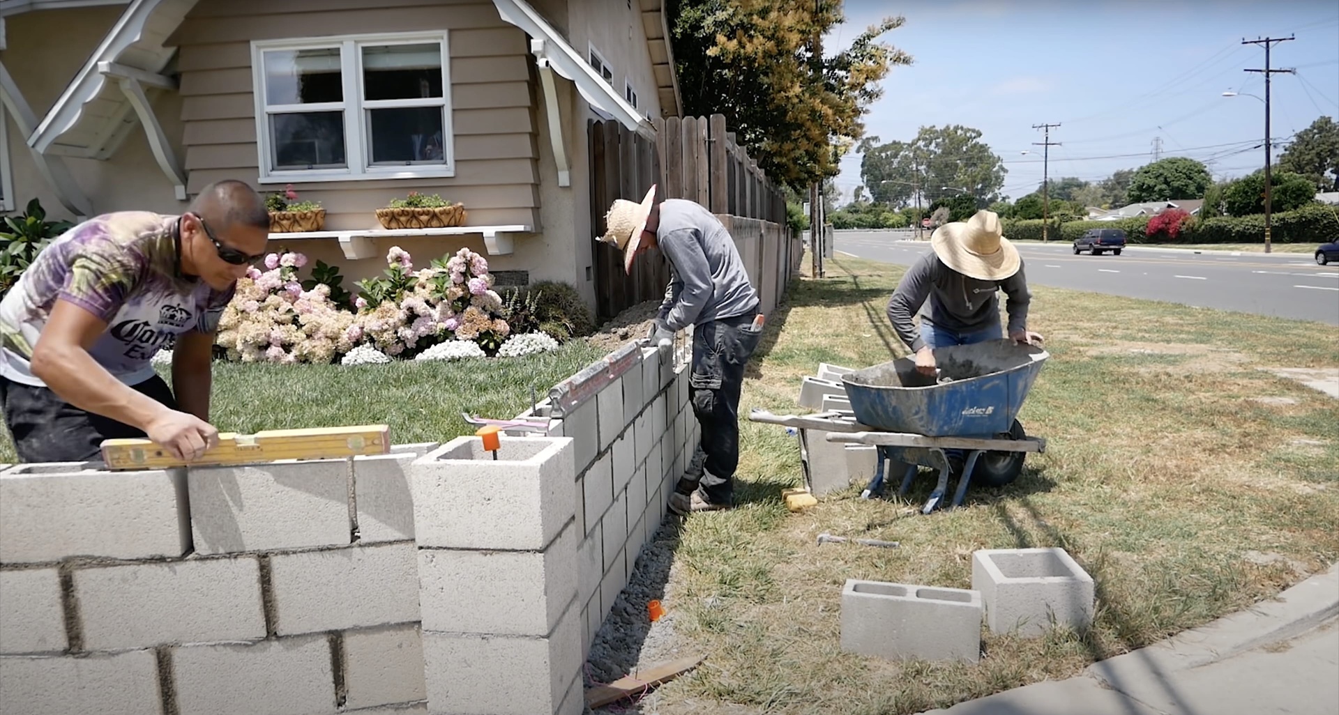 Concrete block retaining wall construction - precision masonry work by Burien Concrete Skilled concrete workers building decorative concrete block retaining wall with proper leveling techniques