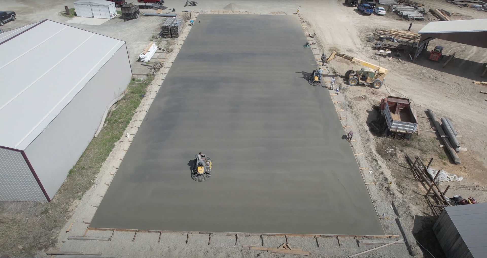 Commercial concrete slab installation - industrial concrete services by Burien Concrete Large-scale commercial concrete slab pour with power trowel finishing equipment in operation